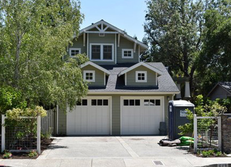 A two car garage with a driveway and trees.