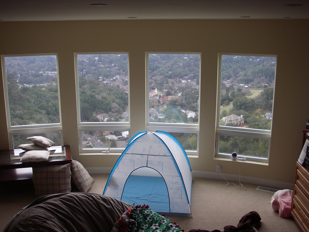 A tent in the middle of a room with large windows.